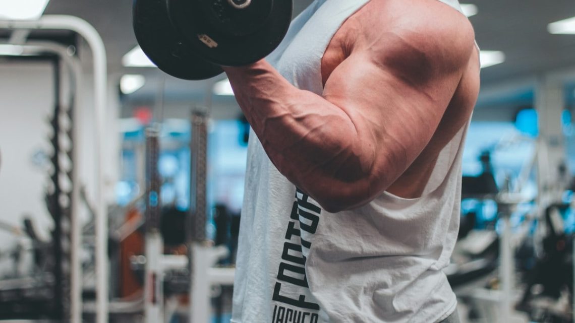 man in white tank top lifting black dumbbell