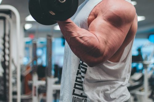 man in white tank top lifting black dumbbell