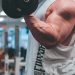 man in white tank top lifting black dumbbell